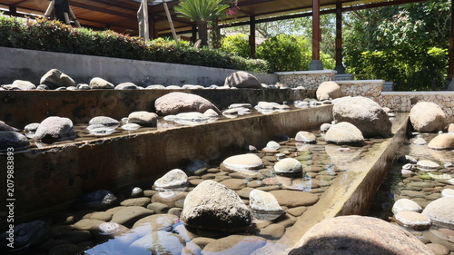 Obraz na płótnie open garden design behind the house using real river stones and a gurgling water