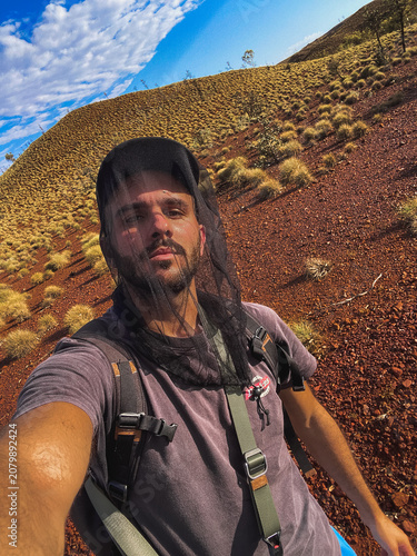Adventurer taking a selfie wearing a fly net in australian outback