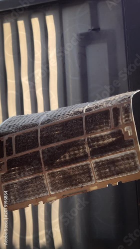 Closeup cropped shot of unrecognizable man examining holding dusty air conditioner filter in hands before cleaning at home. Concept for maintenance of hygiene and pure air to prevent allergies.