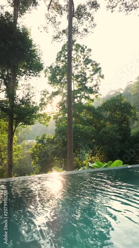 Sunlit infinity pool surrounded by lush tropical rainforest, with vibrant green foliage and warm morning light creating a serene luxury retreat in nature