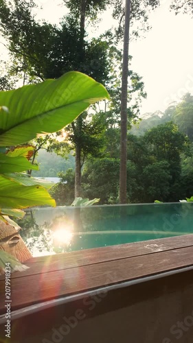 Sunlit infinity pool surrounded by lush tropical rainforest, with vibrant green foliage and warm morning light creating a serene luxury retreat in nature