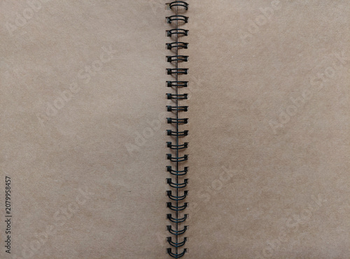 фотографія An open spiral notebook with blank, brown kraft paper pages and black metal coil binding, for stationery, copy space, background, mockup, sketchbook, journal, diary, creative design project concepts