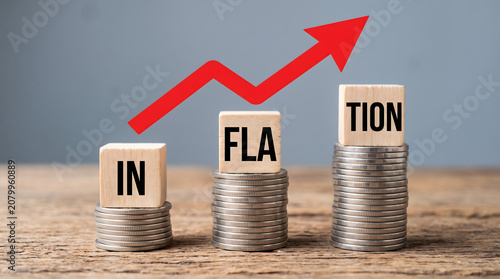 Inflation Concept with Stacks of Coins and Wooden Blocks on Wooden Table with Red Arrow Graph Rising Upwards