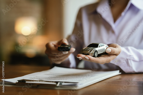 Schilderij op canvas Hands protecting a model car, symbolizing vehicle insurance, financial protection, ownership, and automotive security
