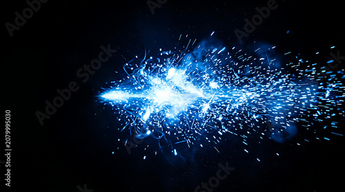 Bright blue electric sparks and particles exploding horizontally against a black background photo