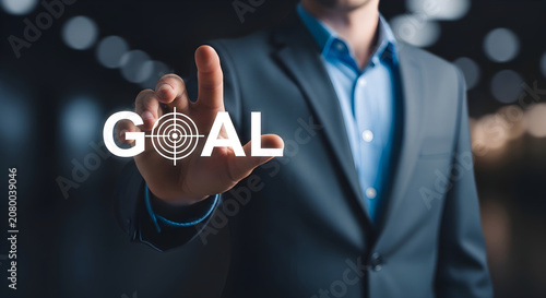 Businessman in suit reaches out to touch a glowing goal target on his hand in a dark room with blurred lights.