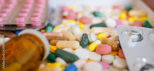 Wide horizontal composition of pharmaceutical capsules, colorful tablets, and blister packs with glass bottle