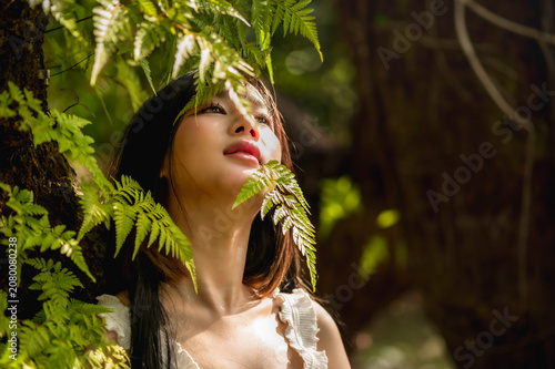 Fotografie Pretty young woman wearing white dress, immersing in nature and enjoying the vib