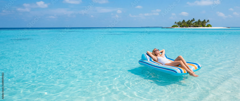 Obraz premium Woman relaxing on a floating air mattress in turquoise tropical ocean