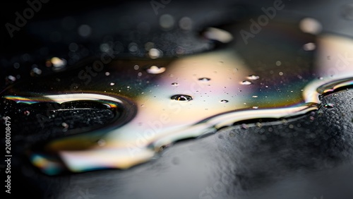 Colorful Rainbow Oil Slick and Water Droplets on Dark Wet Asphalt Close Up