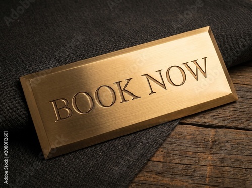 Elegant Brass Book Now Sign on Textured Background.