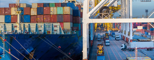 Fotografie gantry cranes loading cargo container ship at a busy commercial port terminal, with trailer trucks lined up on the dock to support global maritime logistics and supply chain operations