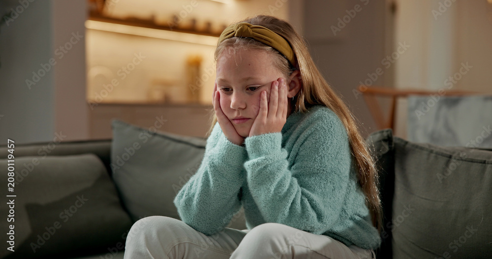 Fototapeta premium Sad, child and thinking in home with loneliness, boredom and mental health crisis in lounge. Thoughts, emotional and kid with depression, overthinking and sorrow expression for bad memories on couch