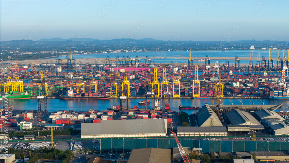 Obraz premium commercial port terminal with cargo ships, container stacks, gantry cranes, storage warehouses, and large car parking lots facilitating global maritime trade and logistics supply chain.