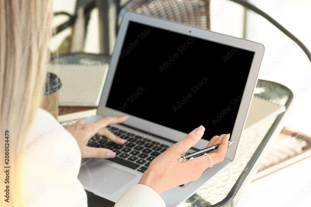 Obraz premium Woman using laptop with pen in hand at glass table