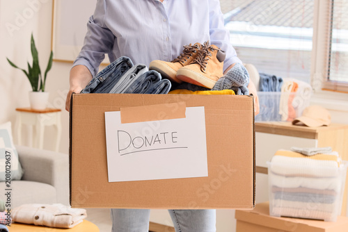 Photos Person holding a donation box filled with clothes and shoes