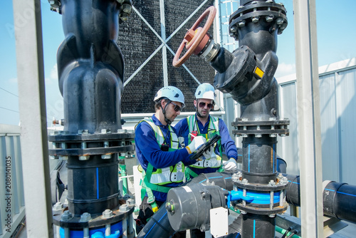 HVAC Engineers Inspecting Rooftop Cooling Tower. Industrial Maintenance Operation.