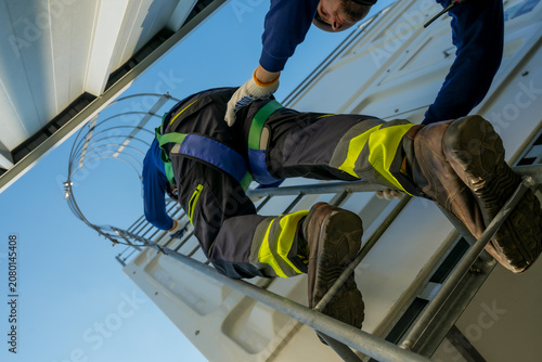 Engineer ascending cooling tower ladder. Rooftop HVAC system maintenance, industrial worker inspecting cooling unit for optimal performance.