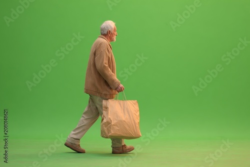 Elderly man walks with brown paper bag (1)