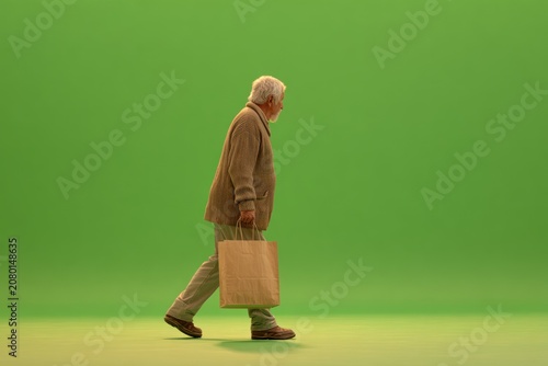 Elderly man walking, carrying paper bag, green screen
