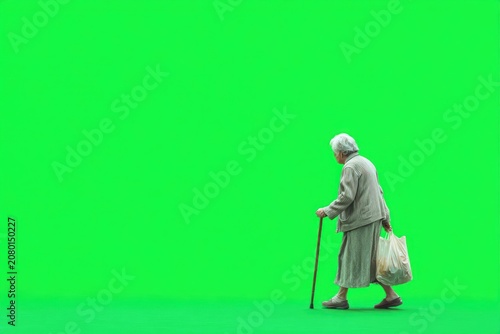 Elderly woman walking with cane on green screen
