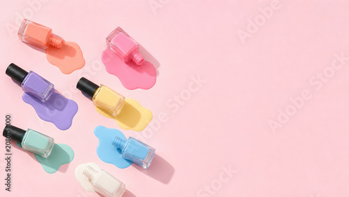 Pastel Nail Polish Bottles Spilled on Pink Background with Copy Space