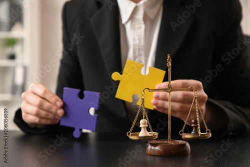 Tableau sur toile Pawns on justice scales against mediator with puzzle pieces at table in office,