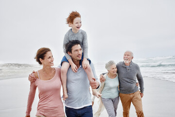 Happy couple spending quality time at the beach with son and grandparents
