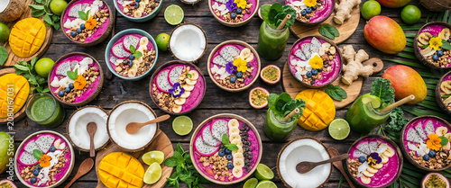 Top-down view of an exotic wooden bar filled with colorful smoothie bowls and fresh tropical fruits with an artistic heavy blur for premium health drink backdrops.