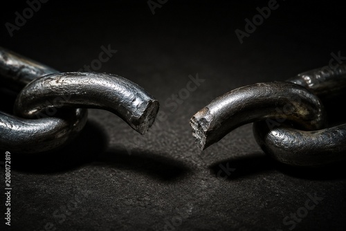 A broken metal chain link separated into two parts.