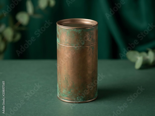 Rustic copper cardboard tube packaging with weathered patina finish on green surface, tea or candle container mockup