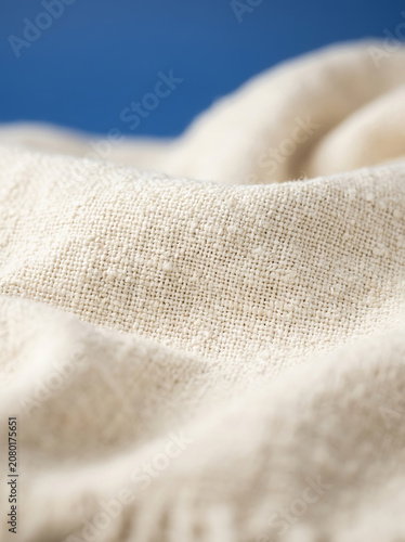 Macro closeup of off white cotton throw blanket with visible weave texture and soft folds perfect for cozy interior design