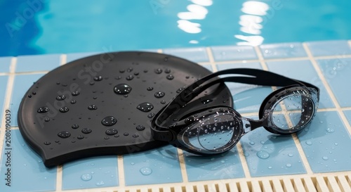 Swim goggles and cap on tiles.