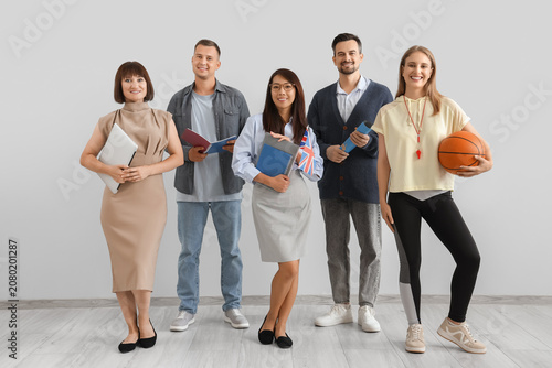 Group of teachers smiling near light wall