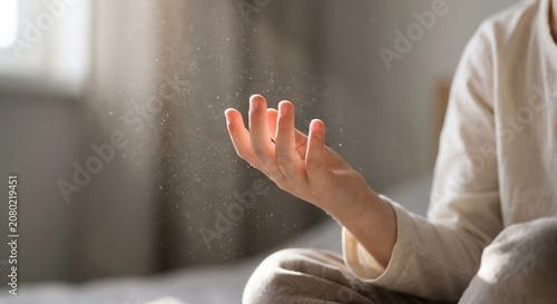Child hand reaching out to catch floating dust particles illuminated by sunlight