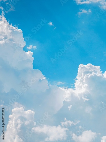 Vibrant vertical view of fluffy white cumulus clouds in bright blue sky evoking freedom inspiration and natural background for corporate advertising.