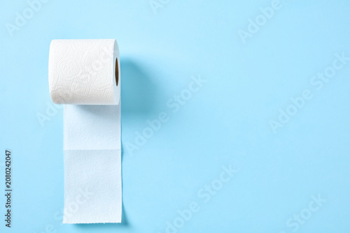 Fotografie Toilet paper roll unrolling vertically on a bright blue background
