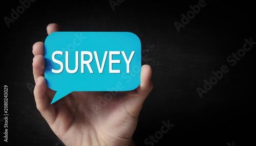 Hand holding a blue speech bubble sign with the word survey written on it