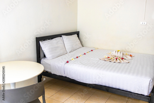 Simple white cheap hotel apartment room bed table chairs Thailand.