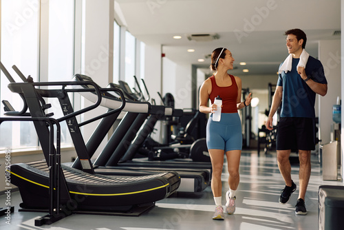 Happy athletes talking while walking through gym.