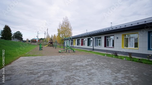 Empty paved backyard includes green grass lawn and sports equipment. Clean contemporary architecture feels peaceful and well organized