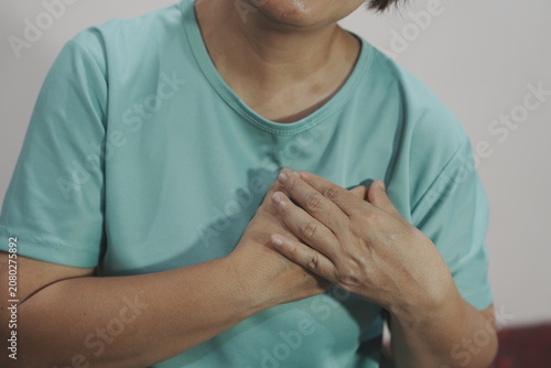 Obraz na płótnie A middle-aged woman, experiencing body aches, sits on a sofa receiving a massage to relieve muscle tension and improve her condition