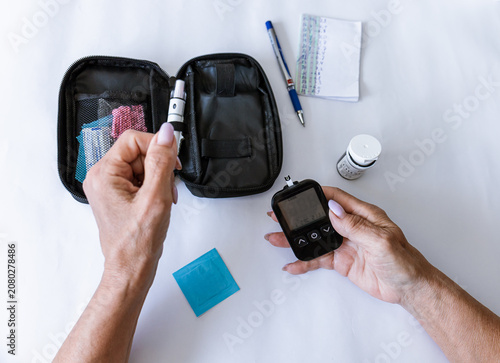 Photos Female hand holding a digital blood glucose meter after measuring blood sugar