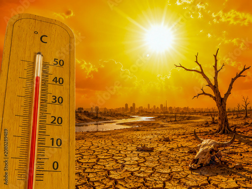 Thermometer showing extreme heat over a dry, cracked landscape with a dead tree and a skull. Conceptual image representing global warming, climate change, and environmental drought.