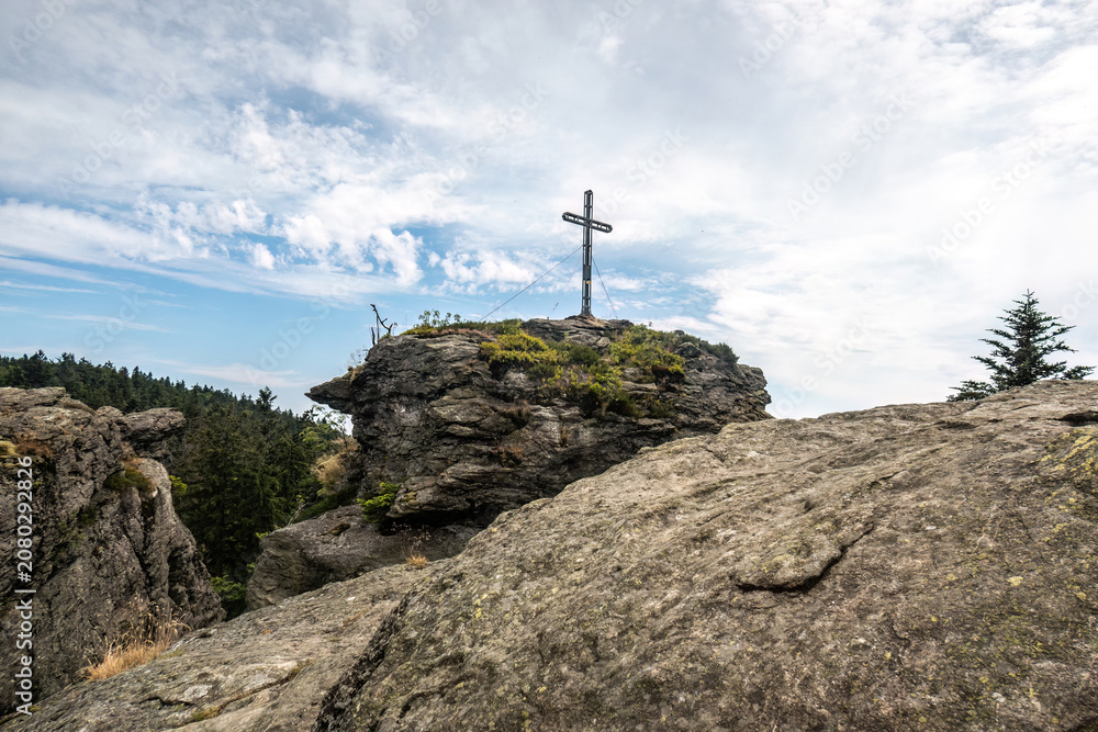 Fototapeta premium Summit cross on the Rauchröhren rock formation along Kaitersberg ridge in the Bavarian Forest, Germany.