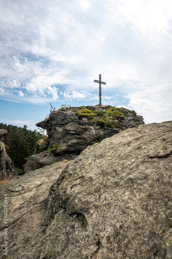 Fototapeta premium Summit cross on the Rauchröhren rock formation along Kaitersberg ridge in the Bavarian Forest, Germany.