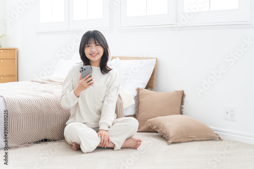 寝室でスマホを使う女性