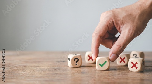 Hand choosing a wooden block with a green check mark from a group of blocks with cross marks and question marks, symbolizing decision making, right choice, and quality evaluation.