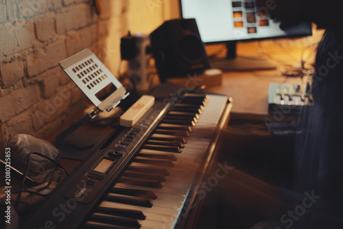 Bild auf Leinwand The Nocturnes — Cinematic abstract of a musician hand moving over a piano keyboard in a dark late-night studio workspace, long exposure motion blur texture with moody warm copper lamp lighting