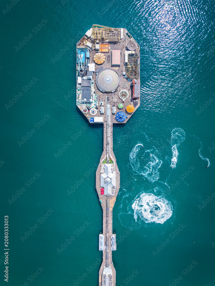 Fototapeta premium Aerial overhead view of the famous Brighton Pier in East Sussex, England, with public amusement park over emerald ocean